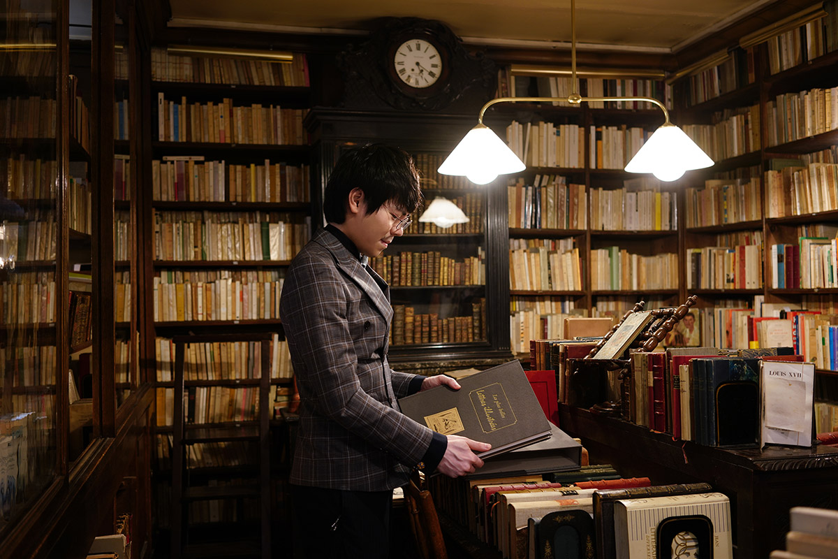 日日好文創品牌主理人在巴黎古書店中翻閱精裝古書，這段旅程成為日後打造大安區古書書寫教室的重要靈感起點。