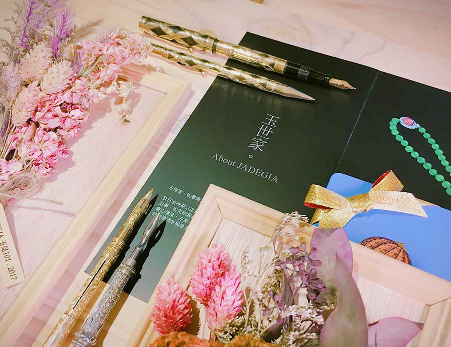 玉世家貴賓活動現場陳列藝術鋼筆、品牌手冊、花藝與贈禮，呈現精緻的精品書寫體驗