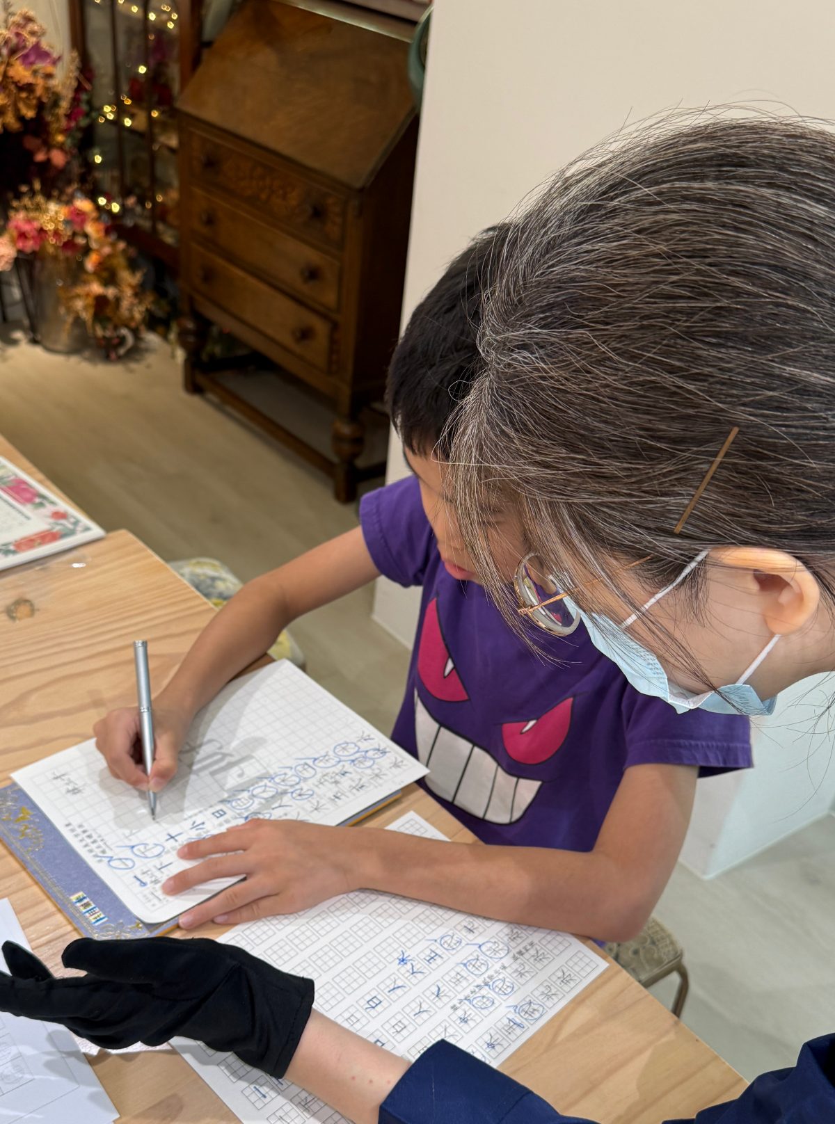 國小孩子於 A3+ 第二次回班複習中專心進行書寫練習,老師在旁協助觀察與指導