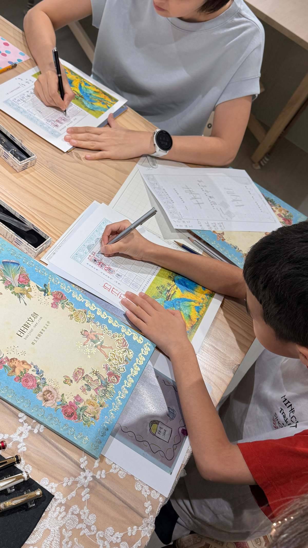 日日好文創 A3 親子書寫課中,媽媽與國小孩子坐在同桌各自練習自己的姓名