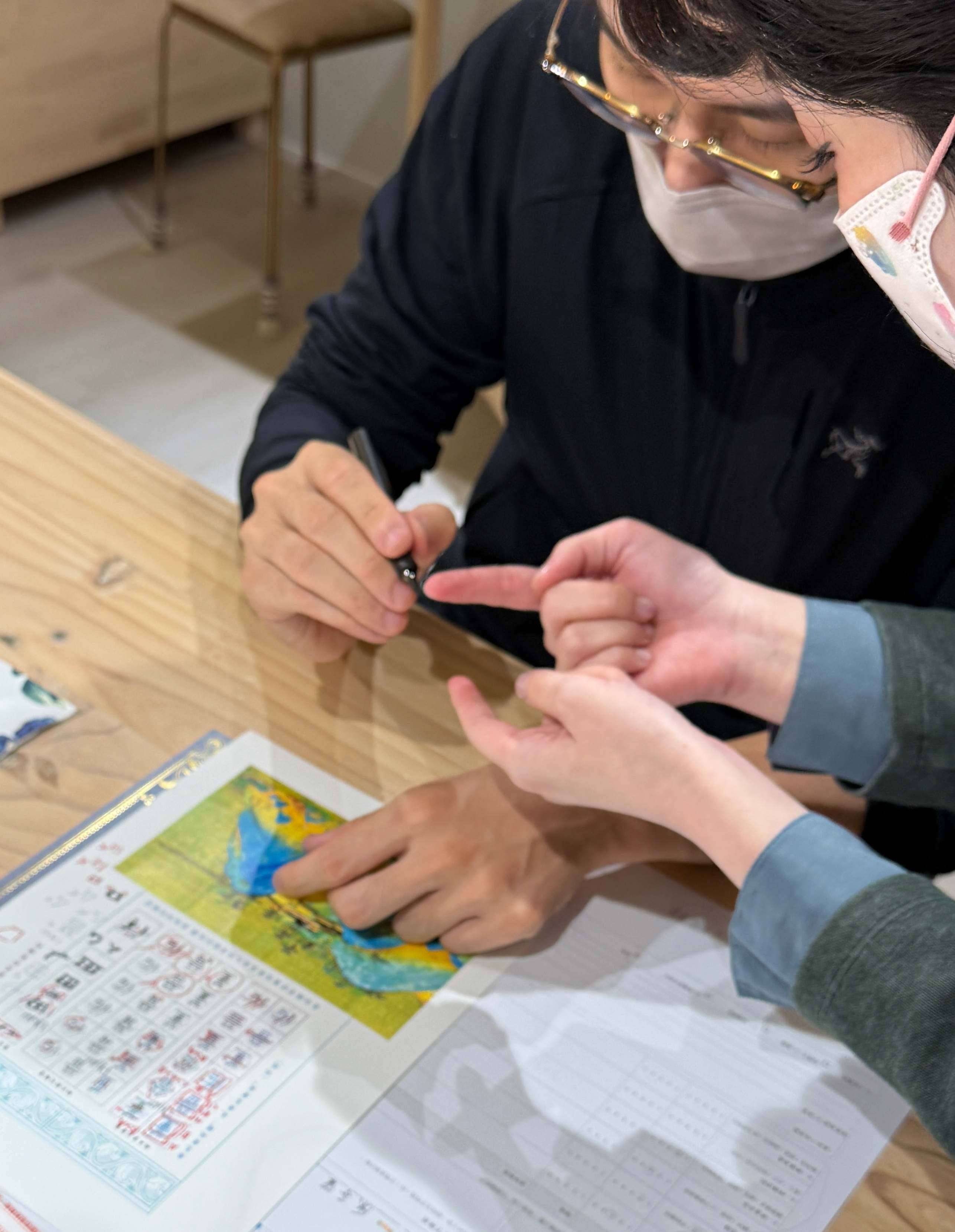 老師近距離觀察學員的鋼筆握筆與手指施力,進行成人書寫姿勢與運筆調整